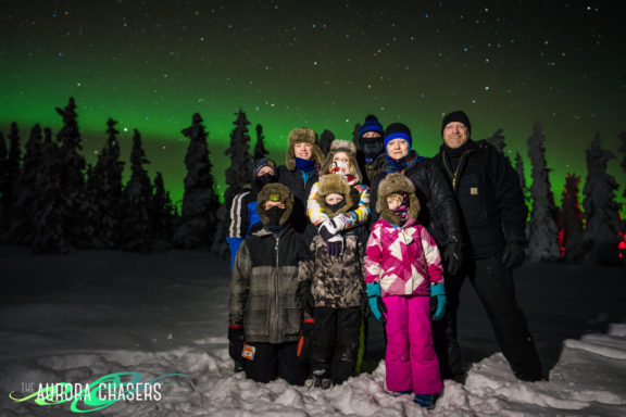 Family Posing in Snow with Aurora Borealis in Background