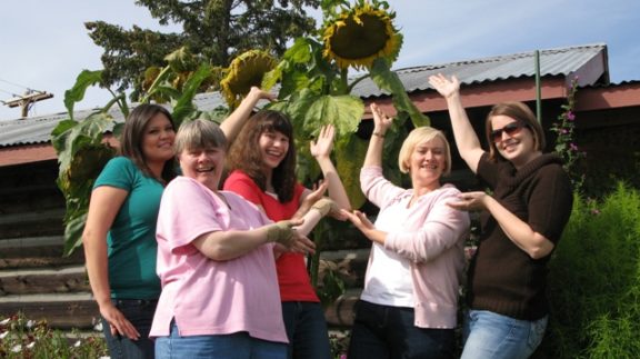 Women posing in front of tall sunflowers